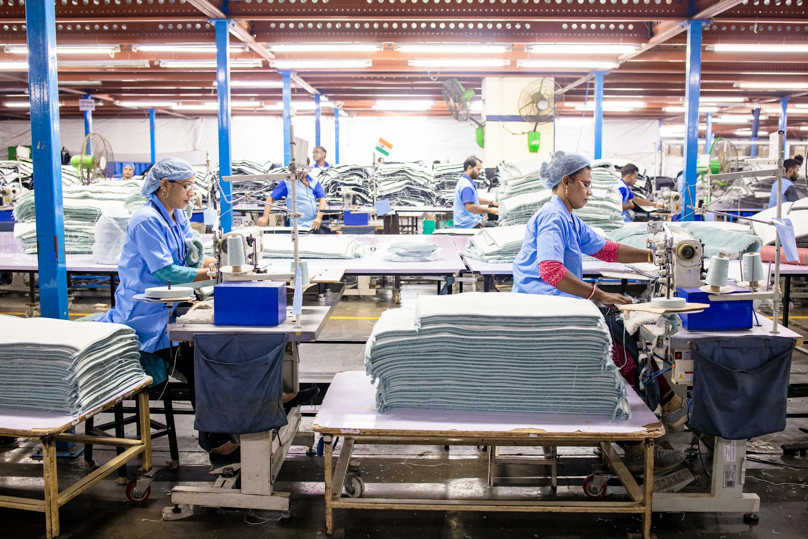 Workers operating industrial sewing machines on a garment production line